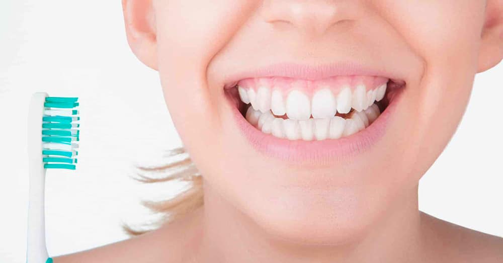 A Smiling Woman Holds A Toothbrush