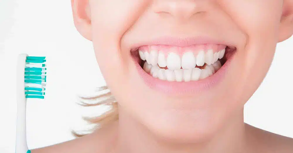 A Smiling Woman Holds A Toothbrush